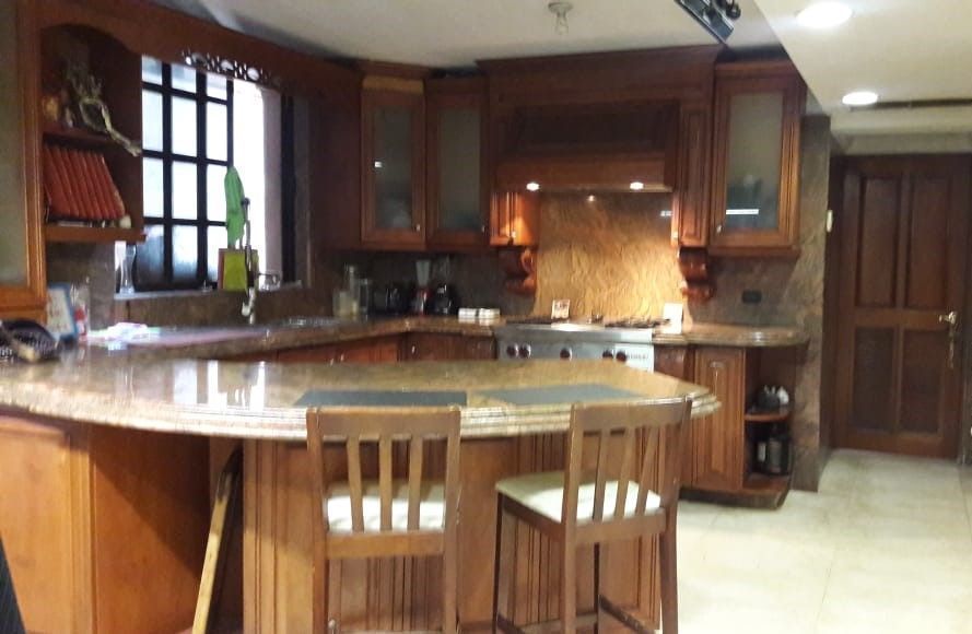 3 de 14: Cocina equipada de madera y barra de granito.