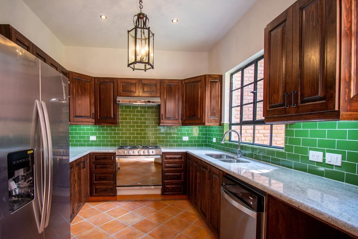 7 de 32: Cocina con azulejos verde, muebles en madera. 