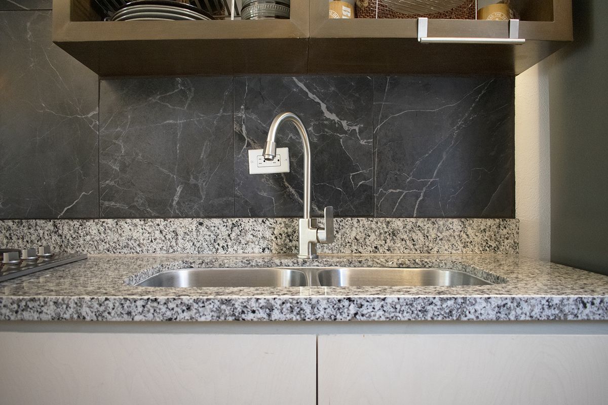 20 de 37: Granite counter with double sink and marble-style wall