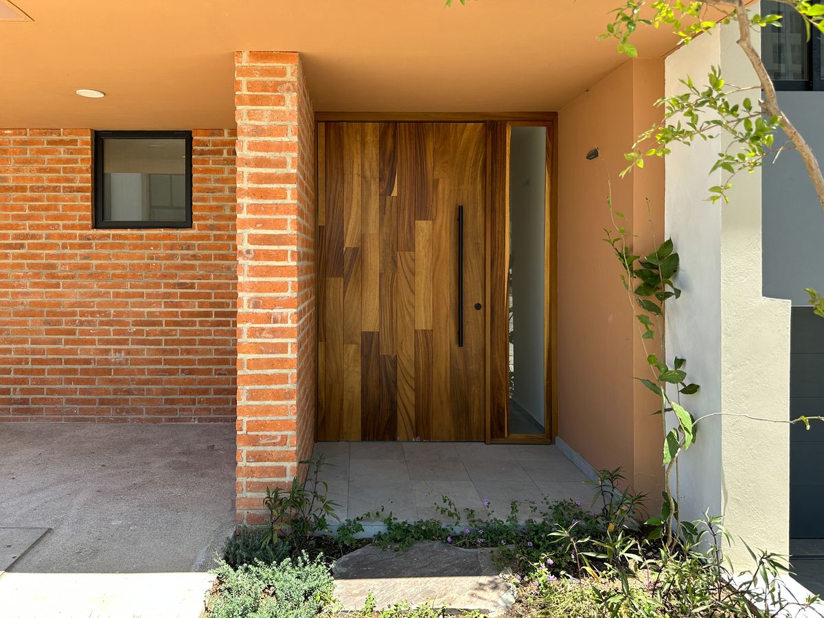 3 de 9: Entrada principal con puerta de madera y muro de ladrillo
