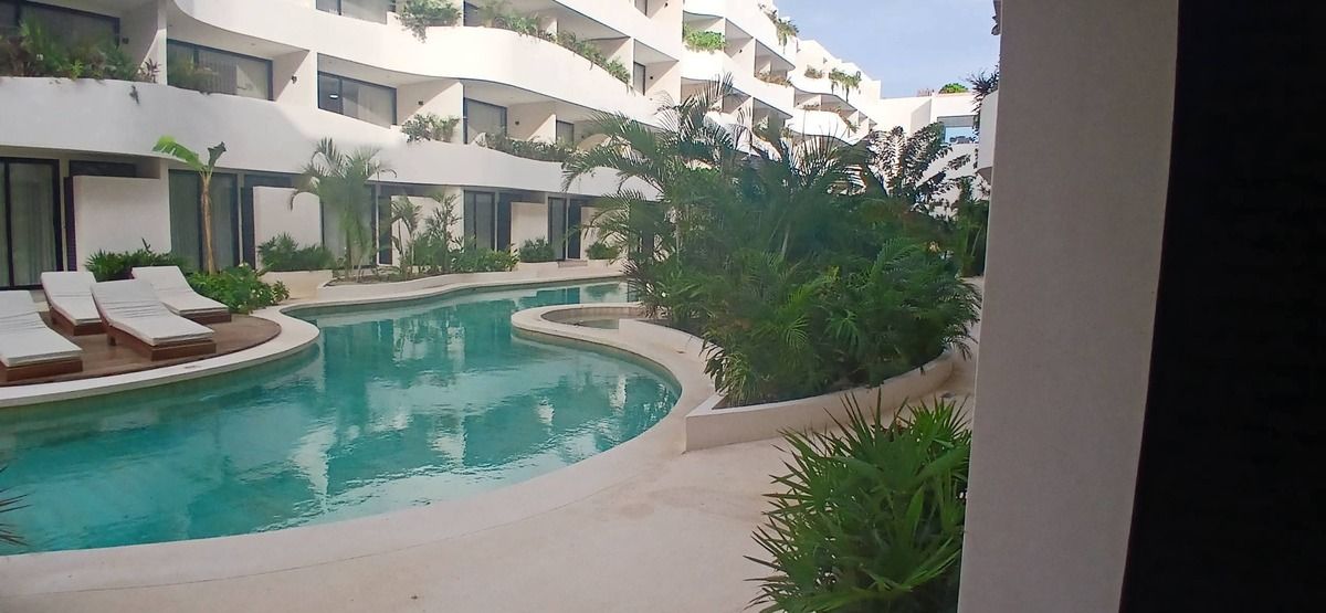 1 de 34: Modern resort pool with white buildings, lush plants.