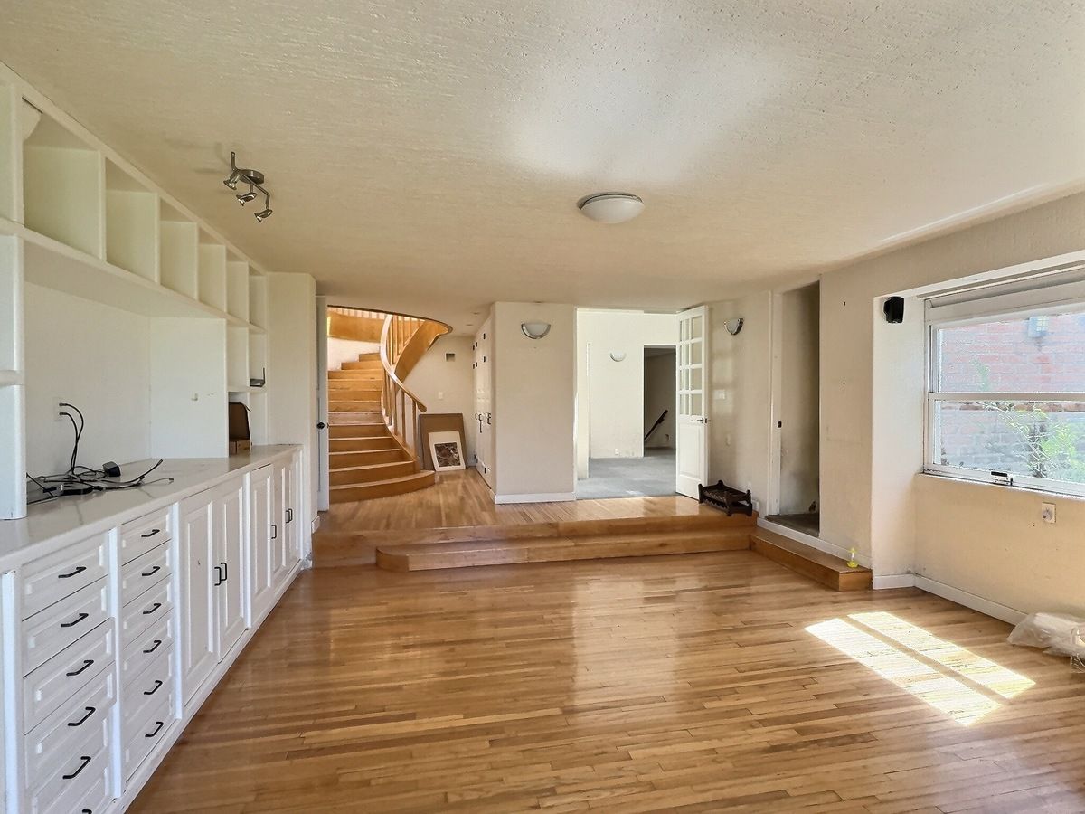 1 of 28: Amplia estancia con piso de madera, y acceso a la escalera